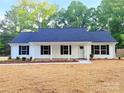 Charming single-story home with a blue roof, white siding, black shutters, and a freshly mulched front yard at 288 Tram Rd, Lancaster, SC 29720