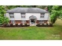 Inviting home exterior with a lush lawn, manicured bushes, and cheerful blue chairs at 3816 Redman Rd, Shelby, NC 28150