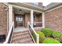 Close-up of front porch with brick steps, white railings, columns, and decorative front door at 525 Chase Prairie Ln, Waxhaw, NC 28173
