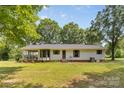 View of the back of the one-story home featuring a screened-in porch and a well-manicured lawn at 5317 Friendly Baptist Ch Rd, Indian Trail, NC 28079