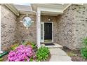 Close-up of a brick house with a front door and flowering bushes at 5722 Kirkwynd Commons Dr, Charlotte, NC 28278
