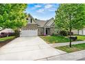 Brick home with a two-car garage, a well-manicured lawn, and mature trees at 5722 Kirkwynd Commons Dr, Charlotte, NC 28278