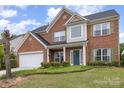Two-story brick home featuring green shutters, a manicured lawn and an attached two-car garage at 5803 Lindley Crescent Dr, Indian Trail, NC 28079