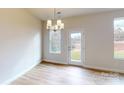 Bright dining area with modern chandelier, hardwood floors, and view of nature from several large windows at 606 Banter Ln # 30, Cramerton, NC 28032