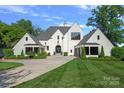Beautiful white brick home with manicured lawn, lush landscaping, and a circular driveway at 7861 Live Oaks Dr, Denver, NC 28037