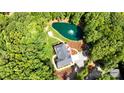 Aerial view of a home nestled among lush trees, complete with a private pond and meticulously landscaped grounds at 7927 Fairmont Dr, Waxhaw, NC 28173