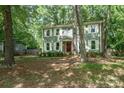 Traditional two-story home with a round window detail, surrounded by mature trees and a lush green lawn at 8936 Rittenhouse Cir, Charlotte, NC 28270