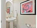 Cozy powder room features pedestal sink, round mirror, and rose artwork at 12641 Glowing Peak Rd, Huntersville, NC 28078