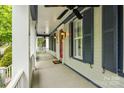 Inviting covered front porch with white columns, blue trim, and a red front door with decorative sconces at 16919 Hedgerow Park Rd, Charlotte, NC 28277