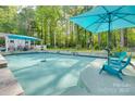 Inviting backyard pool area with umbrella, mature trees, stone surround, and comfortable lounge chairs at 2062 High Pines Rd, Rock Hill, SC 29732