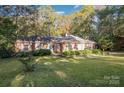 Lovely single-story brick home with green lawn, surrounded by mature trees at 2643 Rolling Hills Dr, Monroe, NC 28110