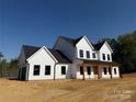 Charming two-story white farmhouse with black windows and wooden porch columns at 4034 Daugherty Rd, China Grove, NC 28023