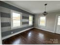 Sunlit bedroom with hardwood floors, striped accent wall, and modern light fixture, offering a cozy atmosphere at 406 S Catawba St, Lancaster, SC 29720