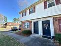 Charming two-story townhome featuring red brick and vinyl siding, complemented by red shutters and landscaped entrance at 5812 Hunting Ridge Ln # A, Charlotte, NC 28212