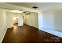 Bright living room with hardwood floors, white walls, and an open floor plan leading to the kitchen and stairs at 5812 Hunting Ridge Ln # A, Charlotte, NC 28212