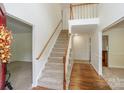 Bright foyer with staircase featuring hardwood floors and white trim, leading to the upper level at 8709 Stratton Farm Rd, Huntersville, NC 28078