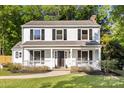 Classic two-story home with white siding, a covered front porch, and well-maintained landscaping at 910 Lightwood Dr, Matthews, NC 28105