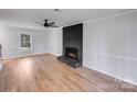 Bright living room featuring hardwood floors, a modern ceiling fan, and a striking black brick fireplace at 12620 Sulgrave Dr, Huntersville, NC 28078