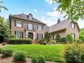 Elegant brick home boasts a manicured lawn, classic shutters, and a charming balcony, enhancing curb appeal at 14650 Trading Path Way, Charlotte, NC 28277