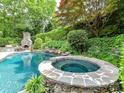 Custom backyard features a unique stone hot tub, luxurious pool and outdoor fireplace at 14650 Trading Path Way, Charlotte, NC 28277