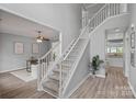 Bright foyer featuring a staircase with white railings, wood floors, and open doorway to the dining room at 156 Pecan Hills Dr, Mooresville, NC 28115