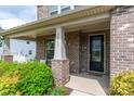 Close-up of a front porch with brick pillars, a black door, and manicured shrubs at 16711 Monocacy Blvd, Huntersville, NC 28078