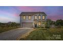 Inviting two-story home featuring a well-lit exterior, attached garage, and landscaped front yard at 2206 Mills Harris Rd, Wingate, NC 28174