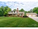 A well-maintained two-story home with attached garage, lush lawn, and mature trees at 4145 Wrangler Sw Dr, Concord, NC 28027