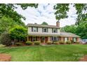 Traditional two-story home with brick facade, green lawn and mature trees offering ample shade at 4145 Wrangler Sw Dr, Concord, NC 28027