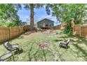 A spacious fenced backyard with a fire pit, seating, a small deck, and mature trees at 703 S Main St, Landis, NC 28088