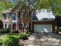 Charming brick home featuring manicured lawn, red door, mature trees, and a convenient two-car garage at 7321 Harrisonwoods Pl, Charlotte, NC 28270
