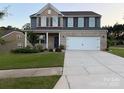 Two-story brick home featuring a two-car garage, manicured lawn and a welcoming front porch at 8901 Powder Works Dr, Huntersville, NC 28078