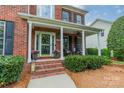 Inviting front porch with brick steps, decorative planters, and cozy seating area at 8902 Whittingham Dr, Waxhaw, NC 28173