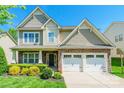 Front exterior of home with stone accents, manicured landscaping, a two-car garage, and a welcoming front porch at 924 Forbes Rd, Fort Mill, SC 29707