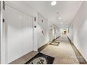 Long interior hallway with multiple white doors, beige carpeting, and elevator access at 127 N Tryon St # 511, Charlotte, NC 28202