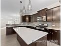 Modern kitchen featuring dark cabinetry, stainless steel appliances, stylish pendant lighting, and a large center island at 133 Stonewater Dr # 16P, Red Cross, NC 28129