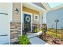 Close-up of the front door with decorative wreath, set within a stone and beige-colored exterior at 15813 Capps Rd, Charlotte, NC 28278