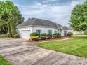 Well-maintained exterior with a long driveway leading to a single-car garage and manicured landscaping at 2603 Willis Dr, Harrisburg, NC 28075