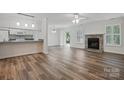 Bright living room featuring wood floors, a stone fireplace, shutters, and modern ceiling fan at 2710 Red Bud Ln, Fort Mill, SC 29715