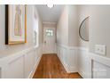 Inviting hallway with hardwood floors, wainscoting, and a view of the front door at 5210 Valley Stream Rd, Charlotte, NC 28209