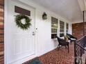 Close up of the charming front porch with chairs and wreath on the front door at 6616 Williams Rd, Charlotte, NC 28215