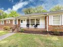 Inviting front porch with brick flooring, chairs, and manicured lawn at 6616 Williams Rd, Charlotte, NC 28215