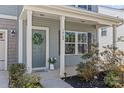 Inviting front porch with gray siding, a wreath on the door, and decorative plants enhancing curb appeal at 1062 River Haven Sw Ave, Concord, NC 28025