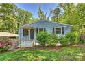 Charming blue home featuring a quaint porch, a well-manicured lawn, and lush green bushes at 1104 Norris Ave, Charlotte, NC 28206