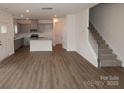 Open-concept living space showcasing wood flooring, stairs, and a view into the modern kitchen at 1119 Overbrook Pl, Wingate, NC 28174