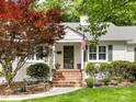Inviting front entrance with brick steps, lush landscaping, and a classic white brick facade at 1209 Yale Pl, Charlotte, NC 28209