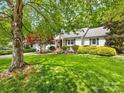 Expansive green front yard with mature trees shading a charming white brick home and landscaped garden at 1209 Yale Pl, Charlotte, NC 28209