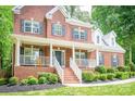 Inviting brick home with a covered front porch, complete with white columns and manicured landscaping at 141 Culpeze Rd, Mooresville, NC 28117