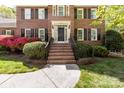 Charming home entrance with brick steps, black shutters, and lush landscaping creating a welcoming feel at 14812 Stonegreen Ln, Huntersville, NC 28078