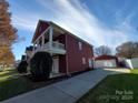 Side view of a two-story house featuring red siding, white trim, detached garage, and well-kept landscaping at 1508 Peaceful Way Dr, Charlotte, NC 28206